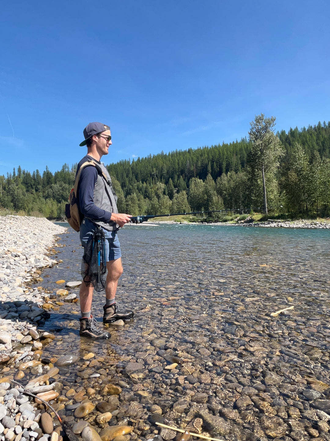 Male angler standing in a river fishing on a beautiful sunny day.