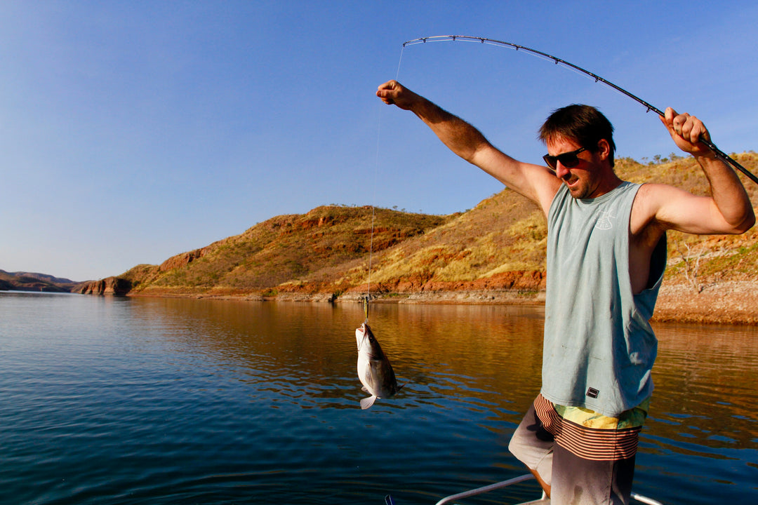 Man fishing a desert lake on a bright sunny day. Man is holding a fish. fish