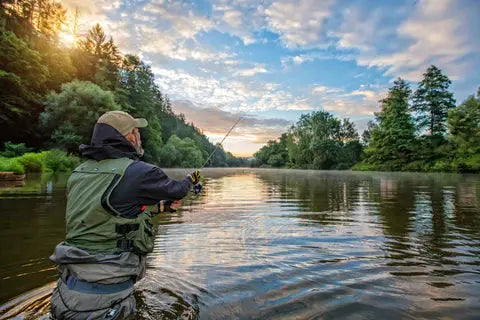 Angler fishing in waist deep water at sunset