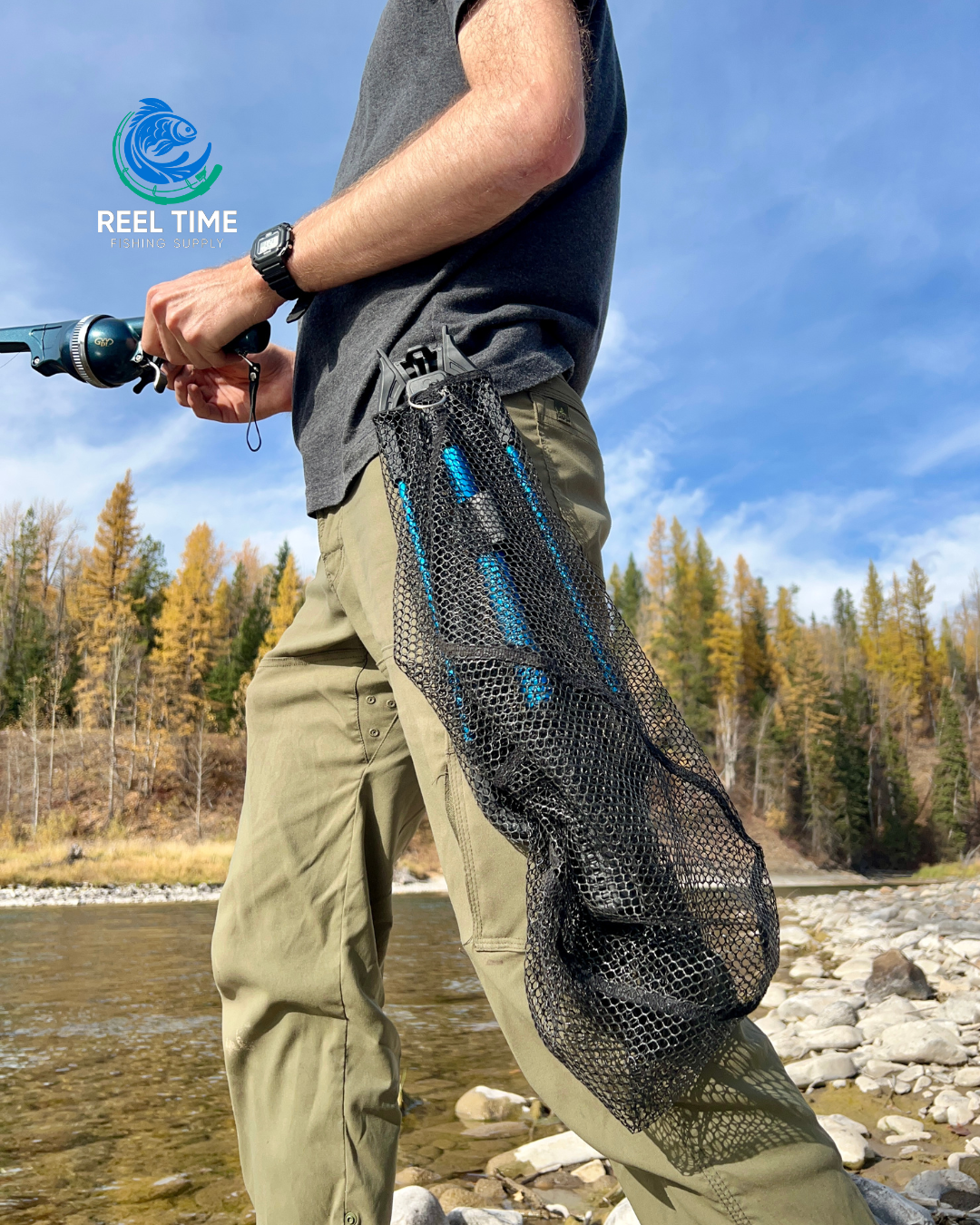 Angler standing by a river fishing. Collapsible landing net is clipped to his belt demonstrating its compact and portable design.